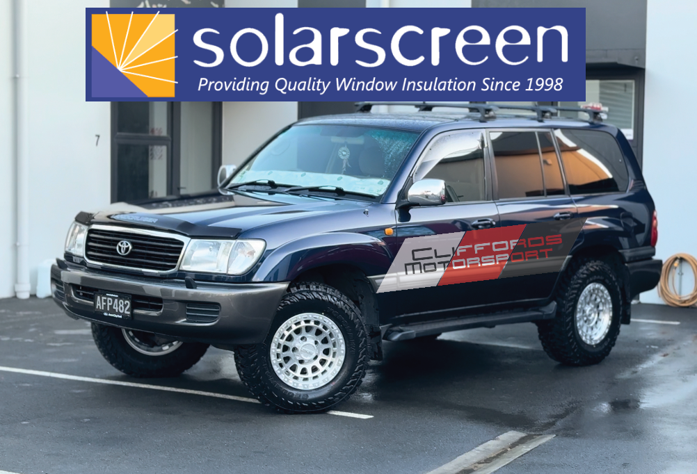 SUV with 'Cliffords Motors' branding in front of a building with 'solarscreen' logo.